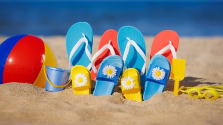 Téléchargez les photos : Tongs familiales, beach ball et tuba sur sable jaune sur fond de mer bleue. Vacances d'été et concept de voyage - en image libre de droit