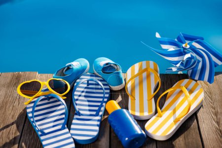 Foto de Chanclas de playa y gafas de sol sobre fondo de madera. Cosas para vacaciones contra el agua azul de la piscina. Vacaciones de verano y concepto de viaje - Imagen libre de derechos