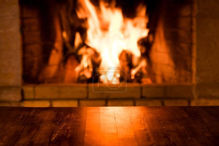 Foto de Antigua mesa de madera vacía contra la quema de madera en la chimenea. Vacaciones de invierno Navidad y Año Nuevo concepto - Imagen libre de derechos