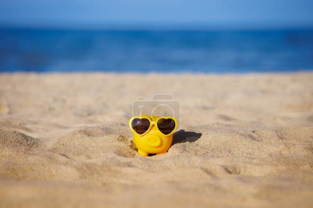 Téléchargez les photos : Tirelire sur la plage. Tirelire sur le sable. Tirelire sur fond marin. Vacances d'été et concept de voyage - en image libre de droit