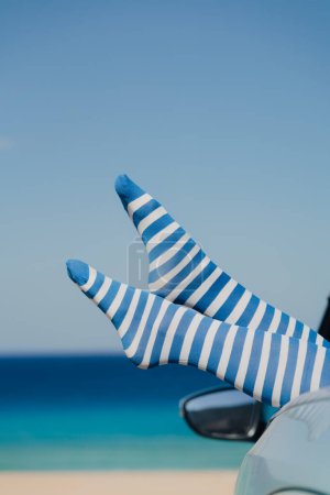 Téléchargez les photos : Jambes de femme sexy portant des bas fendus contre la mer bleue et le ciel. Vacances d'été concéder - en image libre de droit