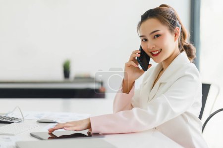 Joven mujer de negocios asiática hablando en un smartphone en una sala de reuniones