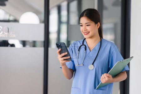 Asian Nurse with Smartphone and Clipboard on Hospital Shift