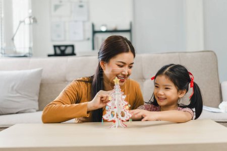 Mother and daughter enjoying crafting a paper christmas tree together at home