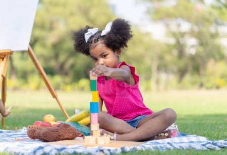 Photo for Cute little girl play toy at the garden, Child girl playing with little wooden toy outdoor - Royalty Free Image
