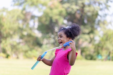 Photo pour Happy kid girl playing with soap bubbles. Active child playing outdoor in the park - image libre de droit