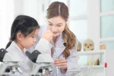 Photo for Elementary science class, Female teacher scientist with kid girl in school laboratory, Science laboratory - Royalty Free Image