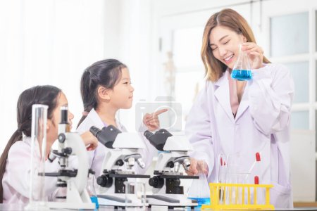 Photo for Elementary science class, Cheerful kids girl with teacher scientist in school laboratory, Science laborator - Royalty Free Image