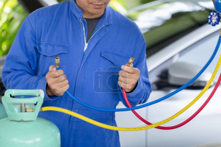 Téléchargez les photos : Technicien homme vérifier la recharge de réfrigérant de système de climatisation de voiture, outil de moniteur de tenue de réparateur pour vérifier et système fixe de climatiseur de voiture, Réparation de climatisation - en image libre de droit