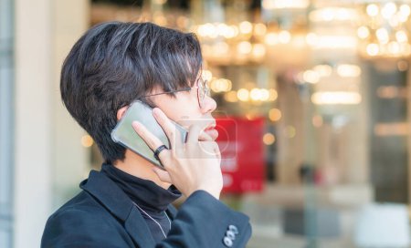 Foto de Joven chico asiático usando el teléfono celular, Hombre asiático hablando en el teléfono inteligente al aire libre - Imagen libre de derechos
