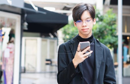 Téléchargez les photos : Jeune homme asiatique regardant l'écran du smartphone, Adolescent garçon dans des lunettes de dactylographie sms, Homme d'affaires en utilisant l'application sur smartphone - en image libre de droit