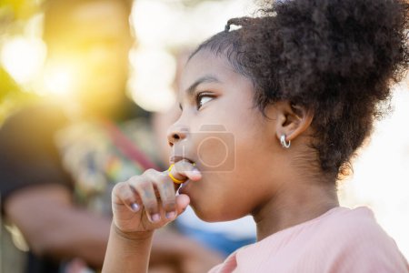Photo for Kid girl with ring pop candy in the park, Girls enjoy ring candy pops, Children play outdoor - Royalty Free Image