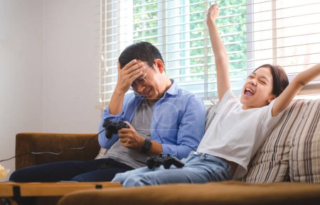 Photo for Asian father and daughter playing video games at home, People doing activities and family concepts - Royalty Free Image