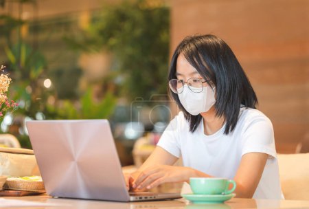 Téléchargez les photos : Fille travaillant à son ordinateur portable, Asiatique adolescente tapant sur un ordinateur portable dans un café - en image libre de droit