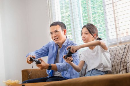 Téléchargez les photos : Asiatique père et fille jouer à des jeux vidéo à la maison, Les gens faisant des activités et des concepts de famille - en image libre de droit
