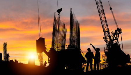 Téléchargez les photos : Silhouette de l'ingénieur et le projet de vérification des travailleurs sur le fond du chantier, chantier de construction au coucher du soleil dans la soirée - en image libre de droit