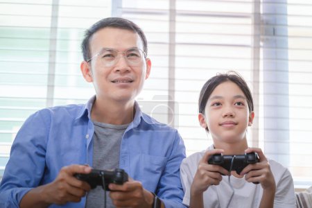 Photo for Asian father and daughter playing video games at home, People doing activities and family concepts - Royalty Free Image