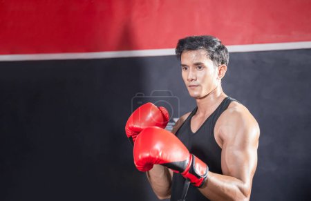 Téléchargez les photos : Portrait d'un jeune athlète fort sportif muay thai boxer combattant dans la salle de gym, boxeur musclé beau combattant homme avec espace de copie - en image libre de droit