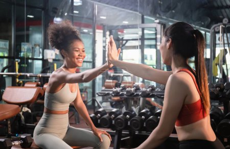 Téléchargez les photos : Concepts de sport et de remise en forme, les femmes sportives se donnent cinq fois l'un à l'autre tout en s'entraînant ensemble à la salle de fitness. - en image libre de droit