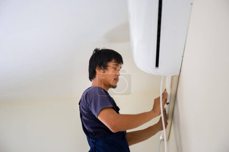 Foto de Técnico hombre instalación de aire acondicionado en una casa de cliente, Joven reparador de la unidad de aire acondicionado de fijación, Mantenimiento y reparación de conceptos - Imagen libre de derechos