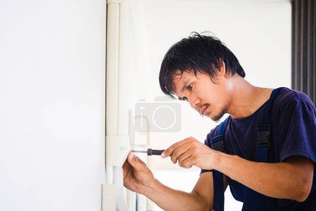 Photo for Electrician using a screwdriver, Technician installing air conditioning in a client house, Repairman fixing air conditioner unit, Maintenance and repairing concepts - Royalty Free Image