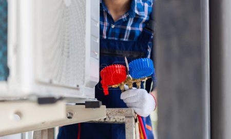 Foto de Reparador que fija la unidad del acondicionador de aire, técnico que instala el aire acondicionado en una casa del cliente, conceptos del mantenimiento y de la reparación - Imagen libre de derechos