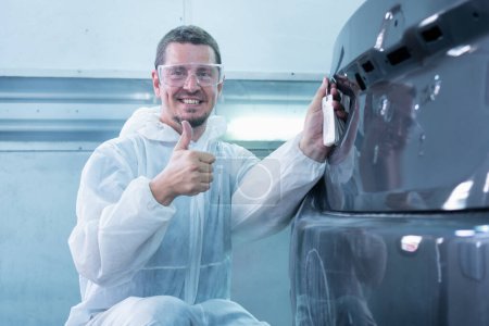 Photo for Worker man showing thumbs up, Mechanic painting car in chamber, Garage painting car service repair and maintenance - Royalty Free Image