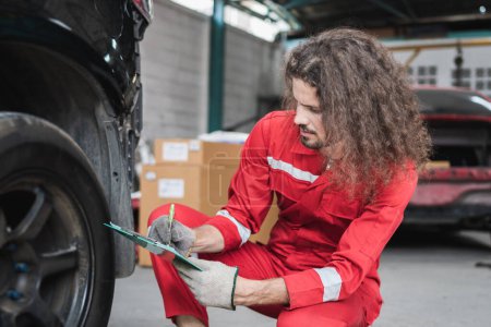 Téléchargez les photos : Jeune mécanicien de voiture caucasien avec une liste de contrôle, Technicien vérification de voiture moderne au garage, concepts de réparation et d'entretien de voiture - en image libre de droit