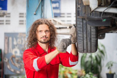 Téléchargez les photos : Portrait d'un jeune mécanicien automobile dans le garage de réparation, Technicien homme travaillant dans l'atelier de réparation automobile, concepts de réparation et d'entretien de voitures - en image libre de droit