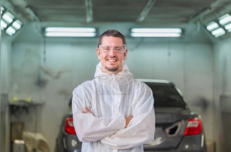 Photo for Mechanic painting car standing with arms crossed in chamber, Cheerful worker man in a repair garage, Garage painting car service repair and maintenance - Royalty Free Image