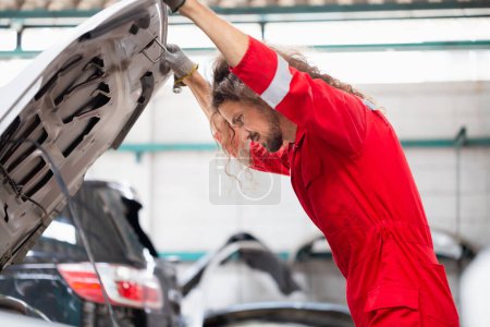 Téléchargez les photos : Mécanicien automobile dans le garage de réparation, Technicien homme travaillant dans l'atelier de réparation automobile, concepts de réparation et d'entretien de voiture - en image libre de droit