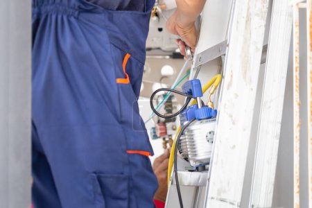 Téléchargez les photos : Technicien homme installant un climatiseur dans une maison cliente, Jeune réparateur réparateur unité de climatisation, Concepts d'entretien et de réparation - en image libre de droit