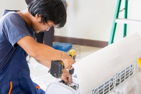 Téléchargez les photos : Jeune réparateur équipe de réparation unité de climatiseur, technicien asiatique homme installant un climatiseur dans une maison cliente, Entretien et réparation concepts - en image libre de droit