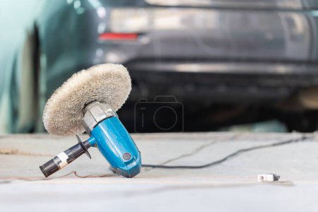 Machine-outil de polissage, Outil de meulage sur le sol avec voiture floue dans la chambre, Garage peinture service de voiture réparation et entretien