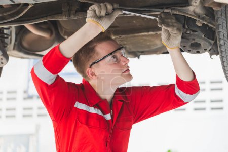 Photo for Auto mechanic working in garage, Technician man working in auto service with lifted vehicle, Car repair, and maintenance - Royalty Free Image