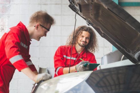 Photo for Technician team checking modern car at garage, Young Caucasian car mechanic with a checklist, Mechanics in uniform are working in auto service, Car repair and maintenance concepts - Royalty Free Image