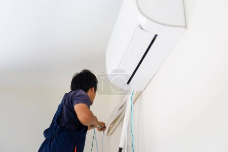 Foto de Reparador que fija la unidad de aire acondicionado, técnico que instala un aire acondicionado en una casa del cliente, conceptos de mantenimiento y reparación - Imagen libre de derechos