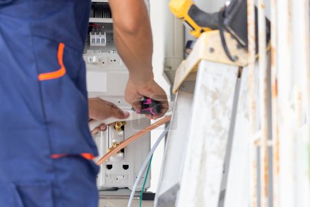 Téléchargez les photos : Technicien homme installant la climatisation dans une maison cliente, Jeune réparateur réparateur unité de climatisation, Concepts d'entretien et de réparation - en image libre de droit