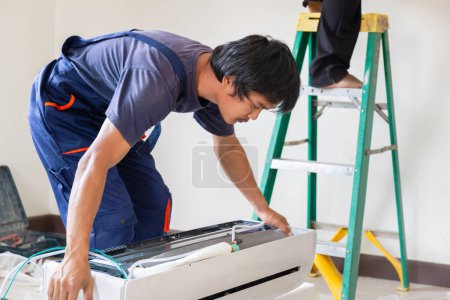 Téléchargez les photos : Technicien homme installant un climatiseur dans une maison cliente, réparateur réparateur unité de climatisation, concepts d'entretien et de réparation - en image libre de droit