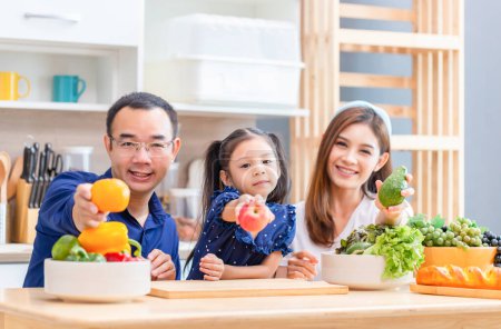 Téléchargez les photos : Père mère et fille cuisiner ensemble dans la cuisine, Heureux concepts de famille asiatique - en image libre de droit