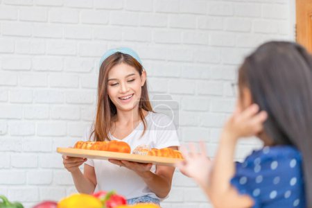 Téléchargez les photos : Cuisine familiale dans la cuisine, Mère tenant un plateau avec du pain dans les mains - en image libre de droit