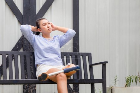 Téléchargez les photos : Les femmes handicapées avec des jambes prothétiques assis se détendre à l'extérieur à la maison. Femme relaxante dans la cour arrière - en image libre de droit