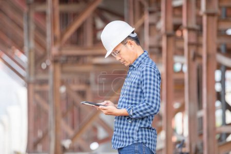 Téléchargez les photos : Projet de vérification de l'ingénieur sur le chantier, Homme en casque avec tablette sur le chantier de construction de l'infrastructure - en image libre de droit