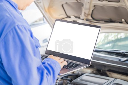 Téléchargez les photos : Auto mechanic working on laptop at mechanic shop, technician diagnosing car engine with a laptop with special program - en image libre de droit