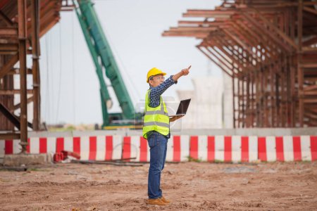 Photo for Man in hardhat with laptop at the infrastructure construction site, Engineer checking project at the building site - Royalty Free Image