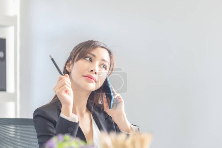 Foto de Empresaria que usa teléfonos móviles en la oficina. Emocionado chica bonita usando smartphone en la oficina, mujer trabajando en la oficina - Imagen libre de derechos
