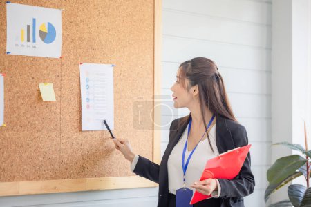 Photo for Portrait of Asian woman making a presentation in front of board, Young female employee explains business data on board in the office meeting room - Royalty Free Image