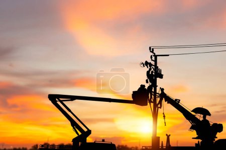 Photo for Silhouette of Electrician officer climbs a pole and uses a cable car to maintain a high voltage line system, Shadow of Electrician lineman repairman worker at climbing work on electric post power pole - Royalty Free Image