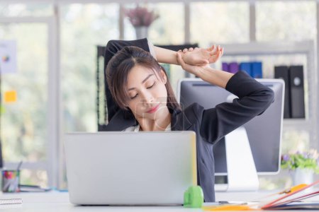 Téléchargez les photos : Syndrome de bureau, femme asiatique faisant exercice d'étirement étirant ses bras dans le temps de travail, officier féminin se sentant fatigué et fatigue étirant pour se détendre - en image libre de droit