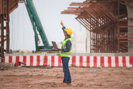 Téléchargez les photos : Ingénieur avec projet de vérification d'ordinateur portable sur le chantier de construction de l'infrastructure, contremaître sur le chantier - en image libre de droit